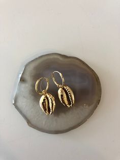 Gold plated cowrie shell charms on small hoop earrings Single Drop Earring For Vacation, Gold Dangle Shell Earrings, Handmade Gold Hoop Earrings For Vacation, Single Shell-shaped Gold Earring, Charm Small Hoop Metal Earrings, Gold Shell-shaped Hoop Earrings, Gold Shell-shaped Hoop Earrings For Pierced Ears, Gold Pierced Hoop Earrings For Beach, Gold Hoop Jewelry For Beach