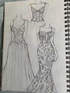 a drawing of two dresses on top of a notebook