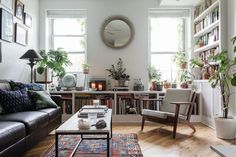 a living room filled with furniture and bookshelves in front of two large windows