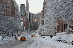 cars driving down a snow covered city street