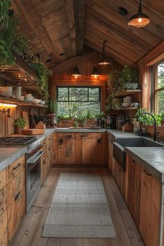 a kitchen with wooden walls and flooring has potted plants on the windowsill