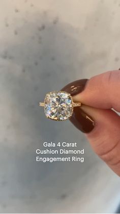 a woman's hand holding an engagement ring with the words gala 4 carat cushion diamond engagement ring