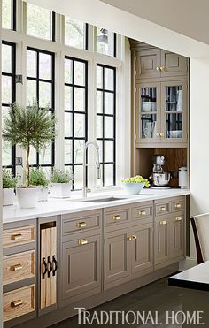 a kitchen filled with lots of counter top space next to a window covered in potted plants