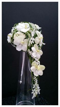 a clear vase filled with white flowers and greenery