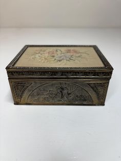 an ornately decorated metal box sitting on a white surface