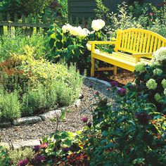 a yellow bench sitting in the middle of a garden