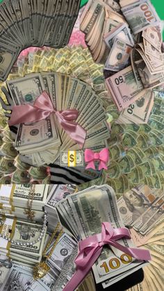 many dollars are arranged in the shape of a fan with pink ribbon and bow on top