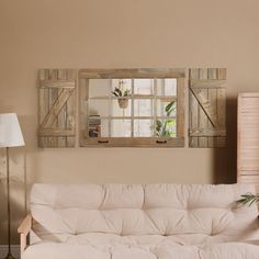 a living room with a white couch and two mirrors on the wall above it's headboard