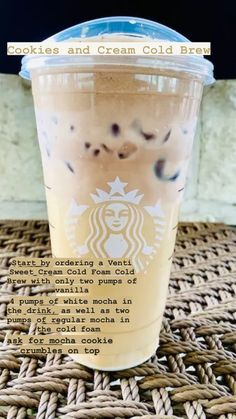 a cup of iced coffee sitting on top of a wicker tablecloth with the words cookies and cream cold brew