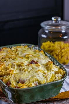 a casserole dish is sitting on a table next to a glass jar with rice in it