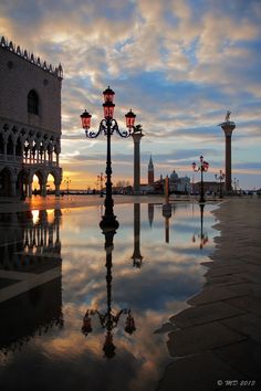 a street light reflecting in the water at sunset