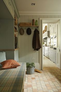 a room with a bench, potted plant and coat rack on the wall next to it