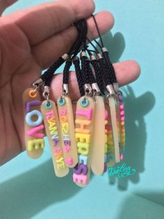 a person is holding some small plastic tags with the words happy birthday on them in multicolored letters