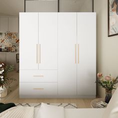 a bedroom with white furniture and flowers in vases on the floor next to it