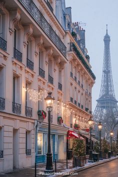 the eiffel tower is lit up in the background as people walk down the street