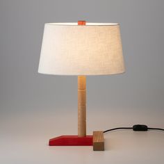 a lamp that is on top of a wooden block with a white shade over it