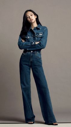 a woman in jeans poses for the camera with her arms crossed and looking off to the side