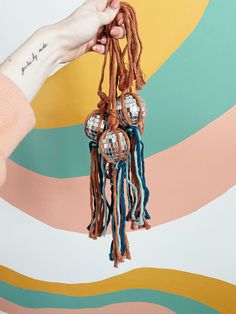 a person holding up some tassels on top of a colorful wall with an abstract background