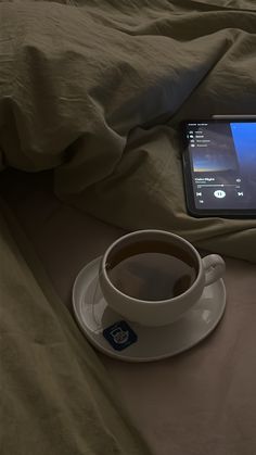 a cup of coffee sitting on top of a saucer next to a cell phone