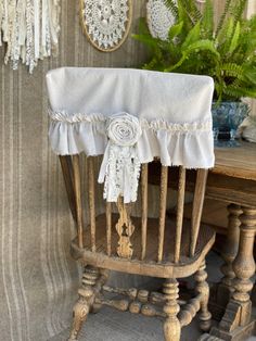 a chair with a white ruffled seat cover on it's back in front of a wooden table