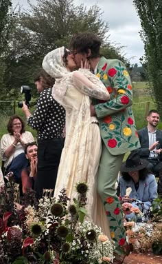 two people kissing each other in front of a group of people sitting on the ground