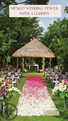 an outdoor wedding venue with flowers on the aisle and thatched gazebo in the background