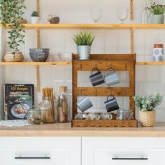 a kitchen counter topped with pots and pans filled with plants next to wooden shelves