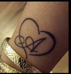 a close up of a person's arm with a heart tattoo on the wrist