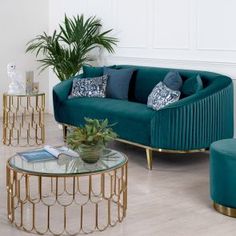 a living room filled with green couches and chairs next to a plant on top of a hard wood floor