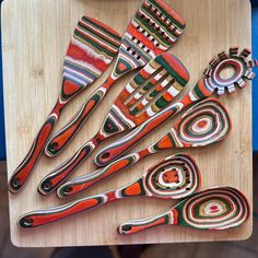 a wooden cutting board topped with lots of colorful utensils