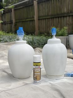 two white vases sitting on top of a table next to a can of spray paint