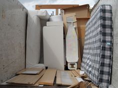 the back of a truck filled with boxes and other items, including an ironing board