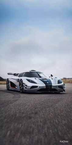 two supercars are parked on the road in front of each other, one is black and white