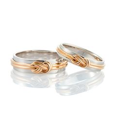 two gold and silver wedding bands with knot detail on each band, set against a white background