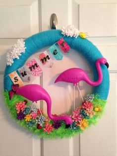 a wreath with pink flamingos hanging on it's side and decorations around the edges