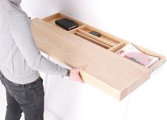 a person standing next to a desk with a cell phone and magazine holder on it