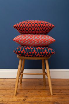 three pillows stacked on top of each other in front of a blue wall and wooden floor