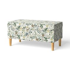 an upholstered footstool with floral print on the back and wooden legs