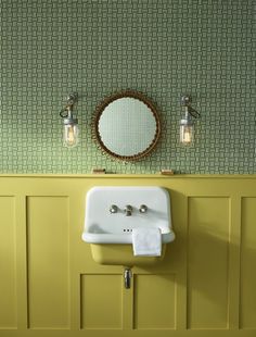 a bathroom sink sitting under a mirror next to a wall mounted faucet with two lights on it