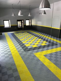 an empty room with yellow and gray checkered flooring on the walls, two lamps hanging from the ceiling