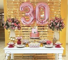 the table is decorated with pink and gold decorations, including an oversized number 30 balloon