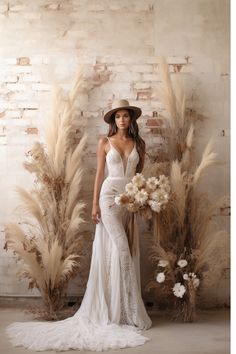 a woman in a white dress and hat standing next to tall pamyliums