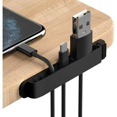 an iphone charging on a wooden table next to a charger and usb cable plugged in