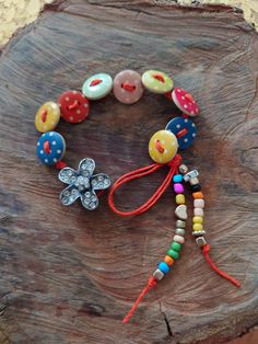 a bracelet with buttons and beads is on a piece of tree trunk that has been cut in half