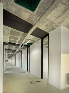 an empty office building with white walls and green ceiling lights on either side of the room