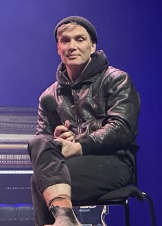 a man sitting on top of a chair in front of a microphone