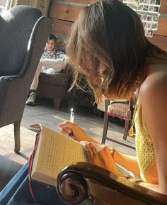 a woman sitting in a chair writing on a piece of paper