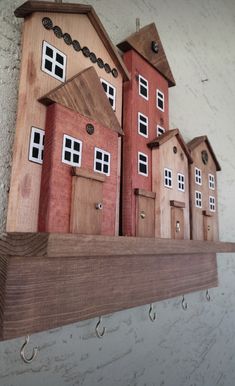 several wooden houses are on a shelf with hooks hanging from the wall behind them,