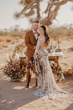 a bride and groom standing in front of a desert wedding arch with flowers on it