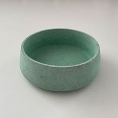 a green bowl sitting on top of a white table